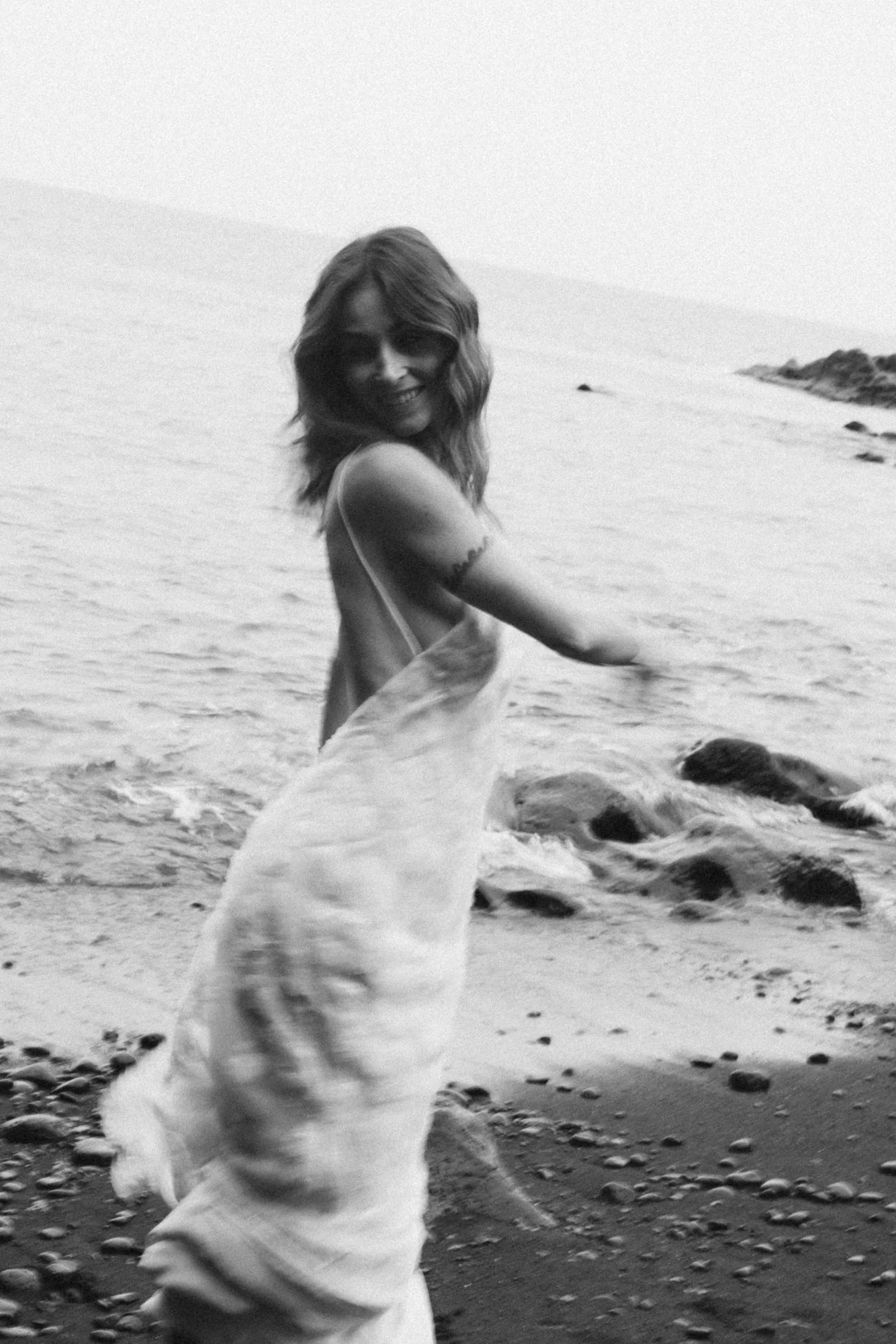Robe 04 de la capsule Meltem en mouvement sur la plage, en noir et blanc