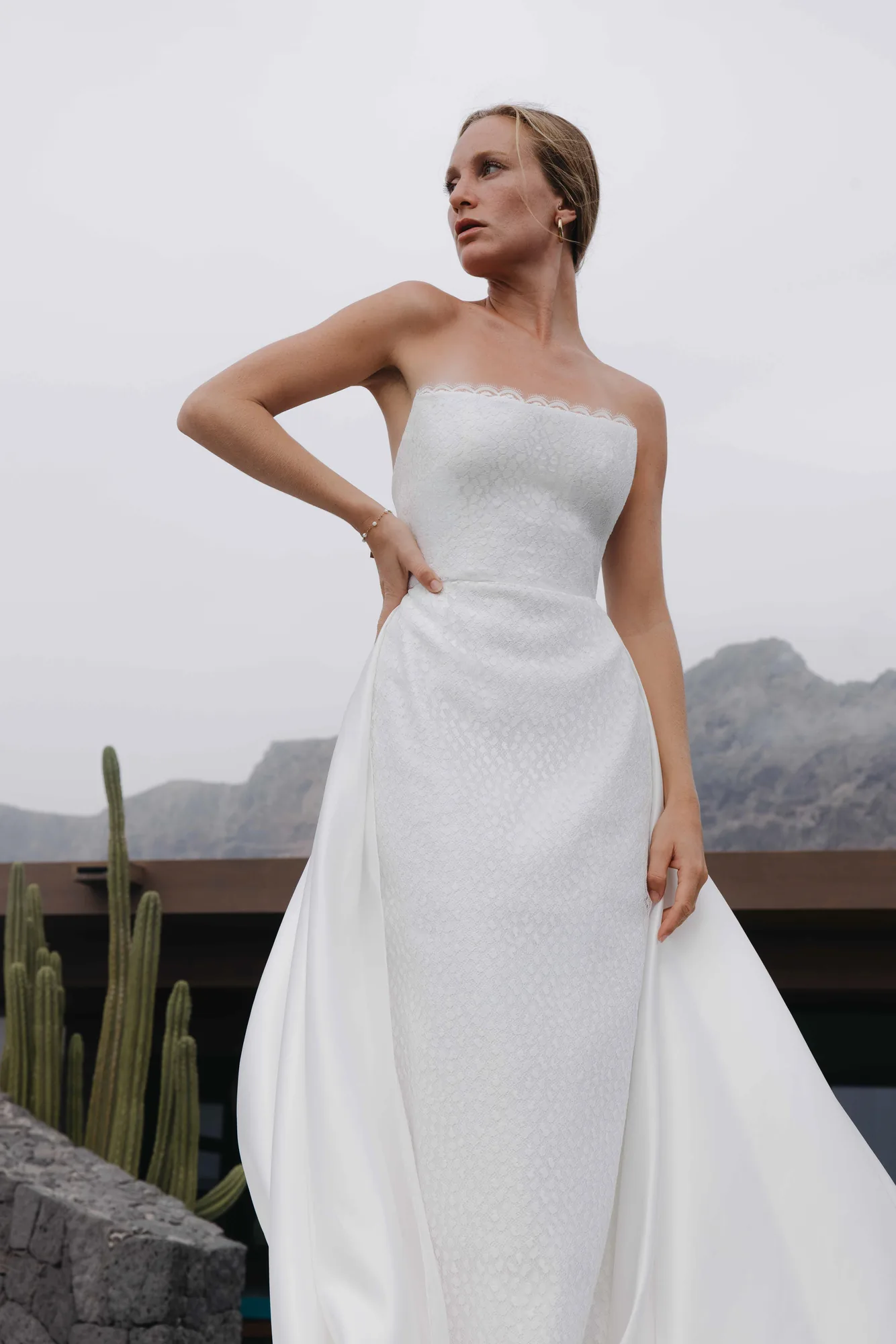 Robe bustier 10 de la capsule Meltem, main sur la hanche, surjupe en satin duchesse aux plis structurés